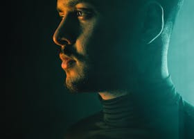 Side profile portrait of a man with dramatic lighting creating a moody atmosphere.